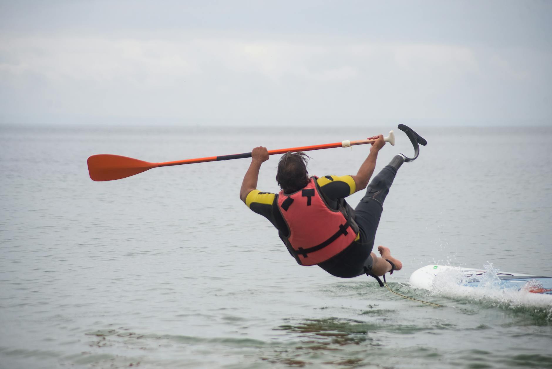 man falling from a standup paddleboard